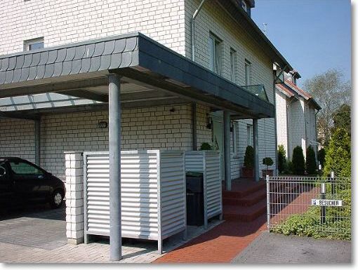 Im Carport integrierter Müllabstellplatz aus verzinktem Stahl und Aluminium-Welle silber, Vordach in Stahl verzinkt mit ESG-Scheiben

